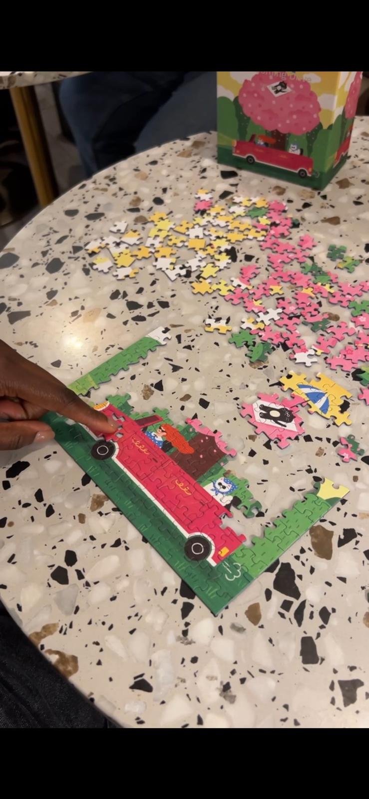 Close-up of a hand placing a piece in the Blooming Drive puzzle