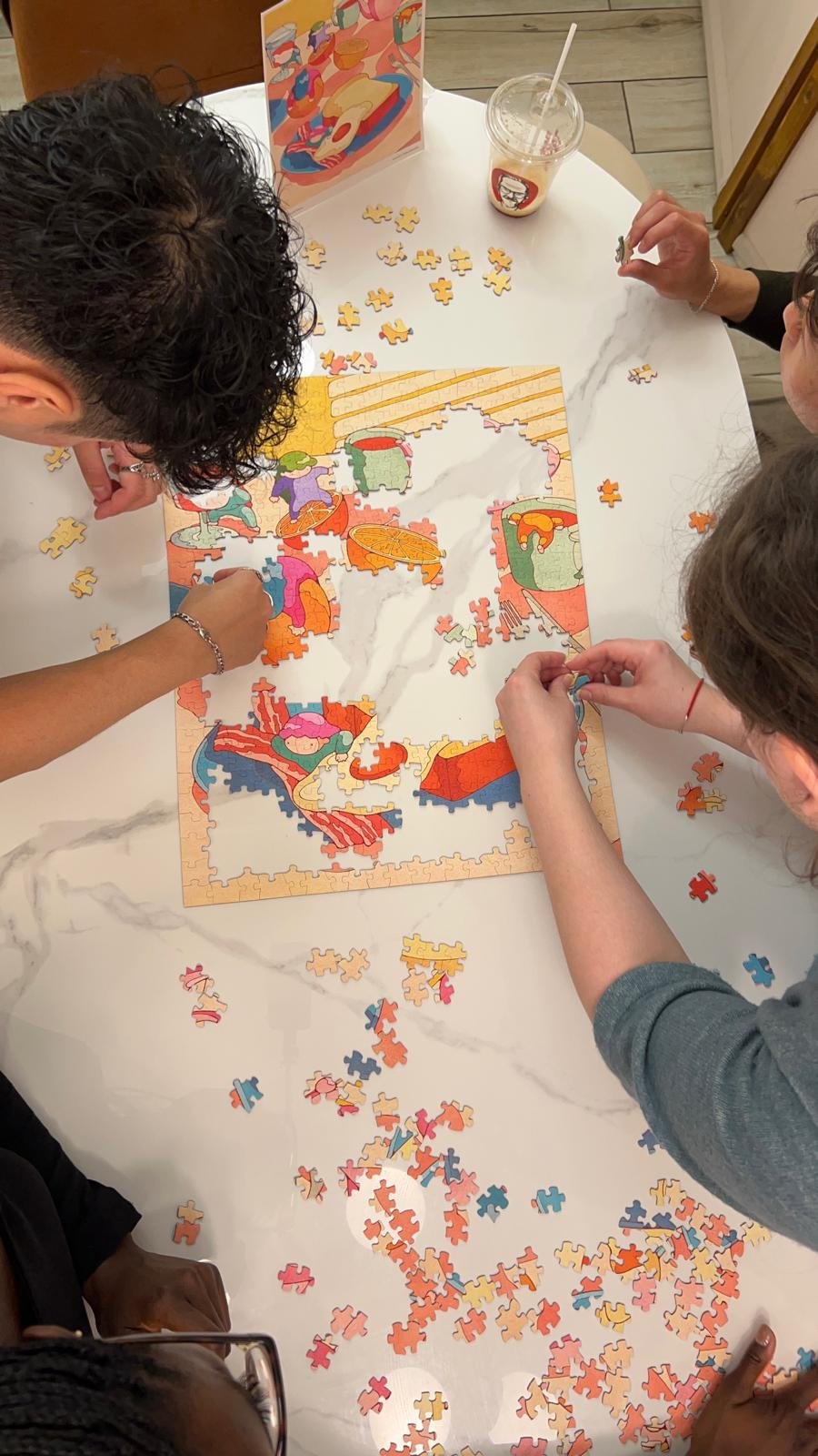 Overhead view of hands piecing together a colourful puzzle