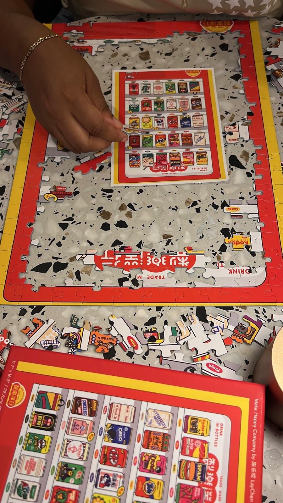 A hand reaching in to place a piece in a snack-themed puzzle