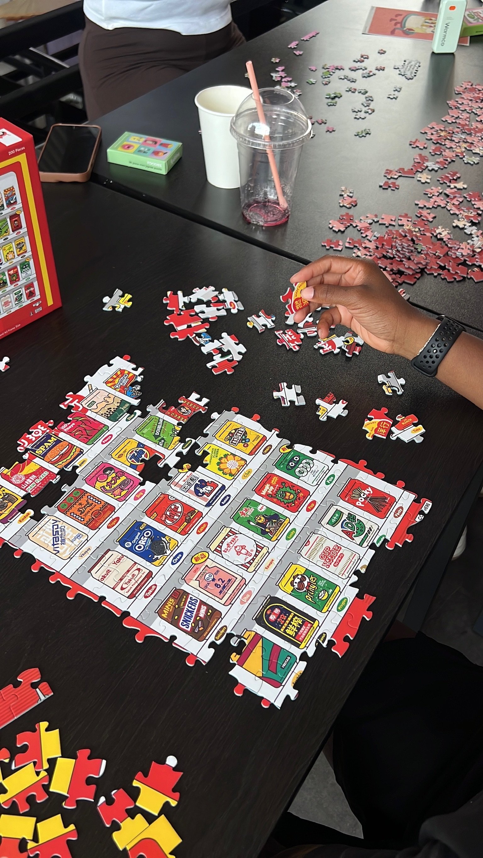 A hand reaching in to place a piece in a snack-themed puzzle