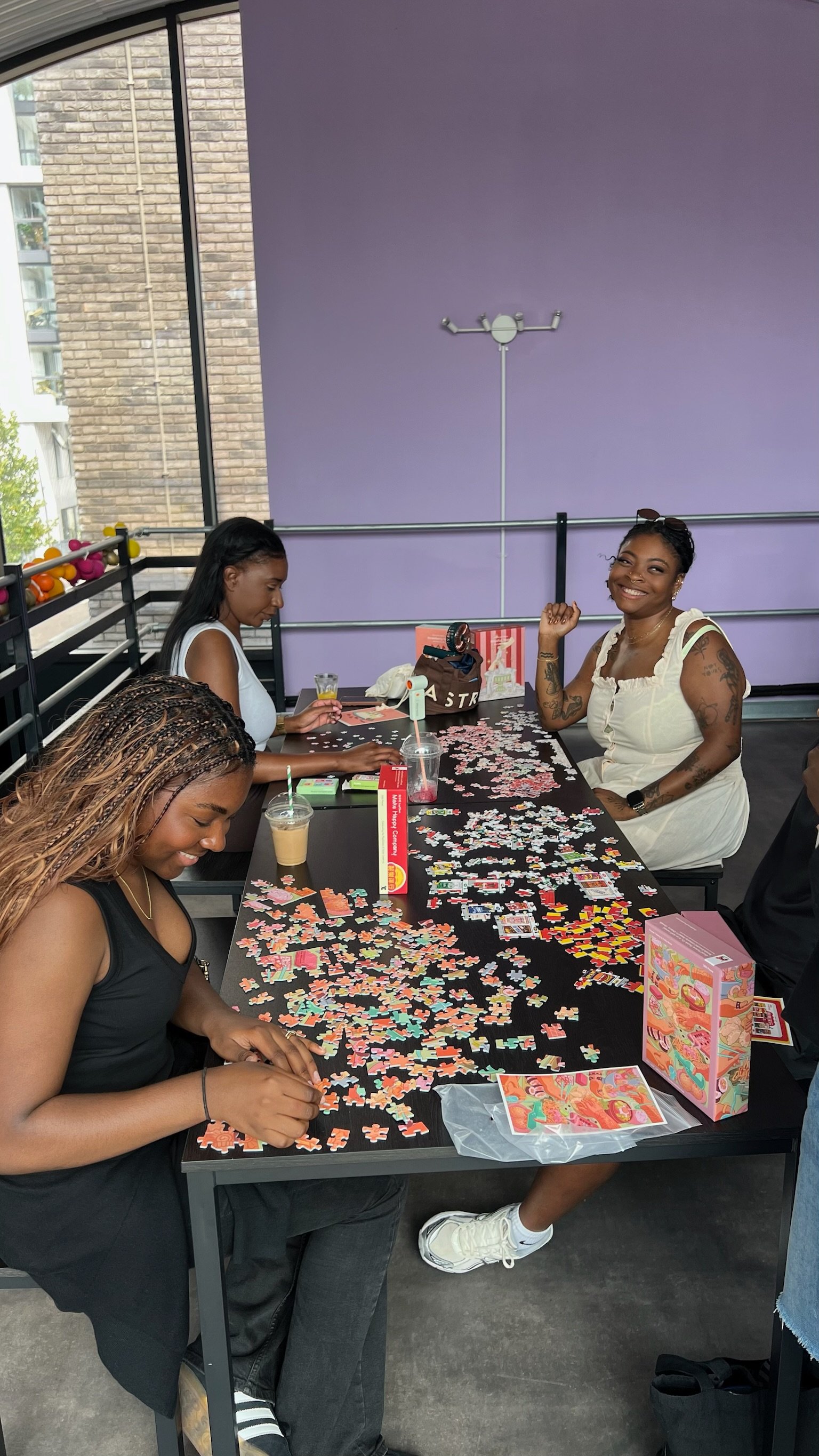 Three people smiling round a table of puzzle pieces
