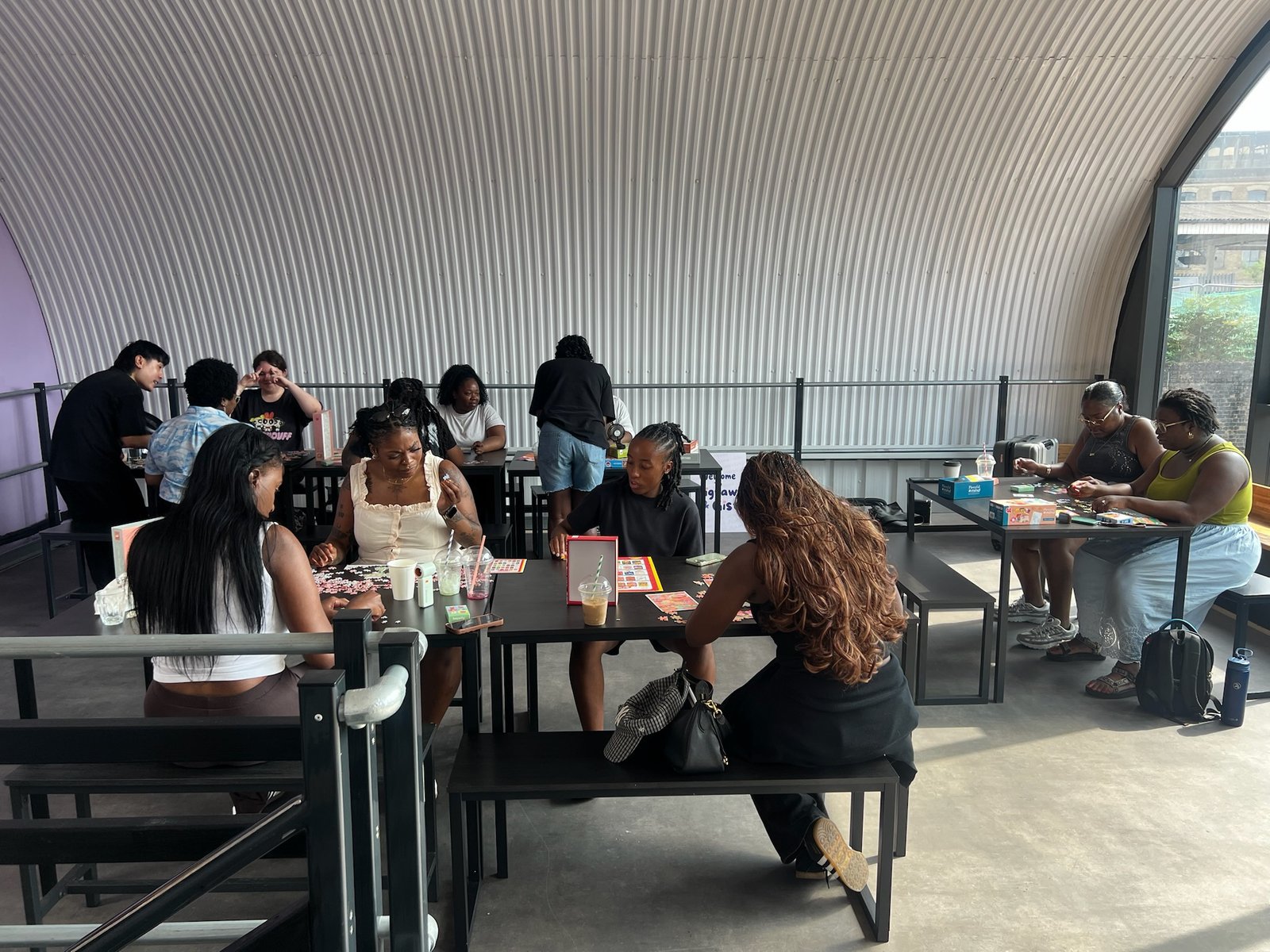A wide overhead view of the room with several tables of people puzzling
